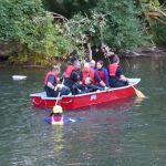 Feuerwehrleute in Boot mit Strömungsretter im Wasser