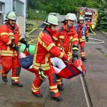 Einsatzkräfte der Feuerwehr tragen verletzte Person