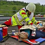 Einsatzkraft des Rettungsdienstes deckt verletzte Person zu.
