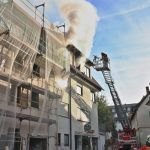 Drehleiter vor rauchendem Gebäude beim Löschangriff